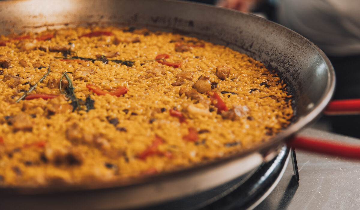 Paella, plato tradicional español de arroz, mariscos y verduras, cocinado en una sartén grande sobre un fuego abierto