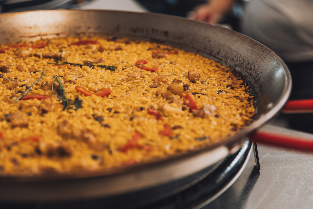 Paella, plato tradicional español de arroz, mariscos y verduras, cocinado en una sartén grande sobre un fuego abierto